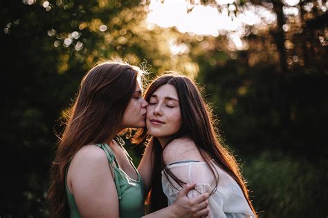 Young Woman Kissing Her Girlfriend On The Cheek In Forest In Summer Photograph By Cavan Images