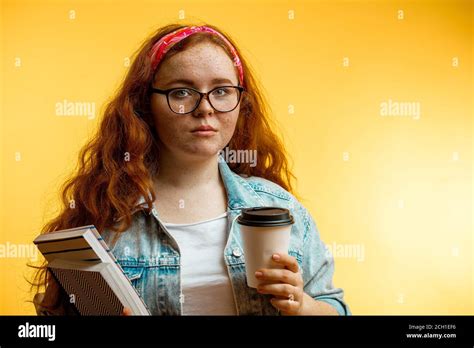 Closeup Portrait Of A Pretty Redhead Freckled Girl With Red Bound On Head Holding Books And