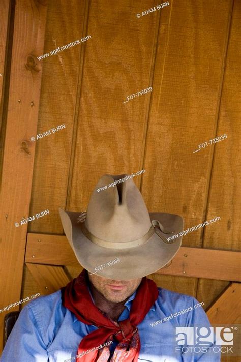 A Cowboy Resting With His Hat Tilted Over His Face Stock Photo