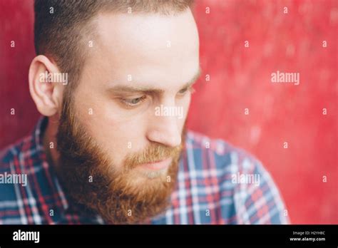 Brooding Bearded Young Man On A Background Of Red Wall Stock Photo Alamy