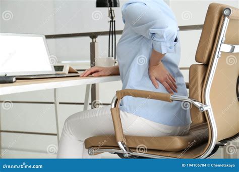 Woman Suffering From Back Pain At Workplace In Office Stock Photo
