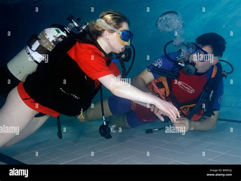 Young Woman Learning To Scuba Dive In Pool With Instructor Teaching