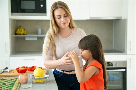 Mamá Dando A Su Hija Un Vaso De Agua Para Beber Mientras Cocina