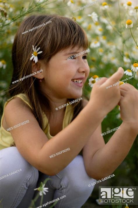 Smiling Cute Girl Crouching In Meadow Stock Photo Picture And Royalty
