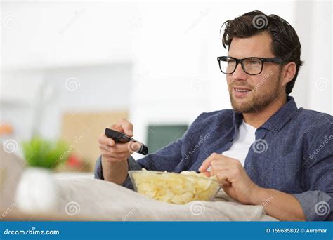 Man Sitting On Sofa Watching Tv And Eating Chips Stock Photo Image Of