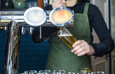 Female Bartender Tapping Beer In Bar Pouring From Tap Into The Glass