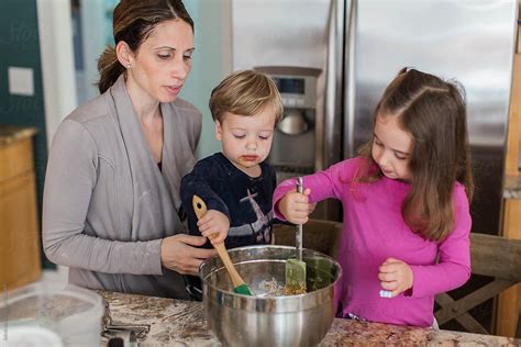 Mother Big Sister And Little Brother Making Cookies In A Kitchen By