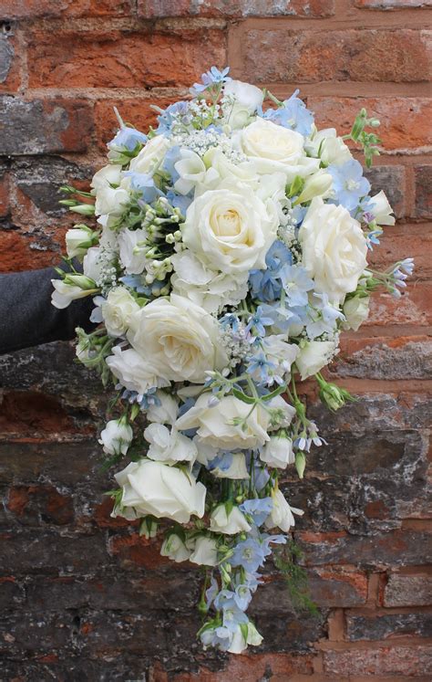 cascading bridal bouquet in pale blue and ivory flowers avalanche roses blue delphinium