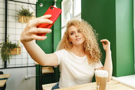 Beautiful Curly Blonde Woman Taking Selfie While Sitting At The Table