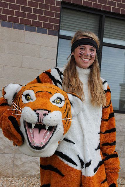 A Woman In A Tiger Costume Is Holding A Stuffed Animal On Her Arm And