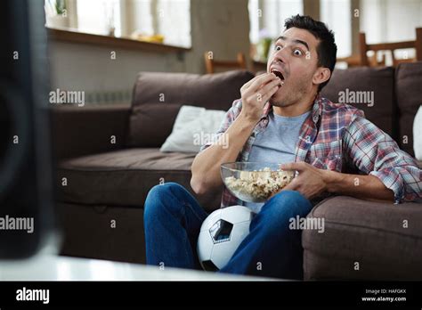 Astonished Guy Eating Popcorn While Watching Curious Tv