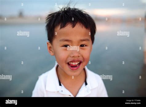 Portrait Of Happy Boy Standing At Beach During Sunset Stock Photo Alamy