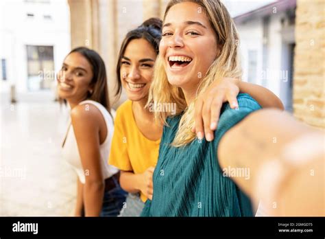 Portrait Of Three Cheerful Multiethnic Female Friends Taking Selfie With Phone On City Street