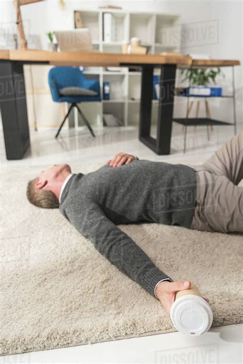Unconscious Man Lying On A Floor In Office And Holding Disposable