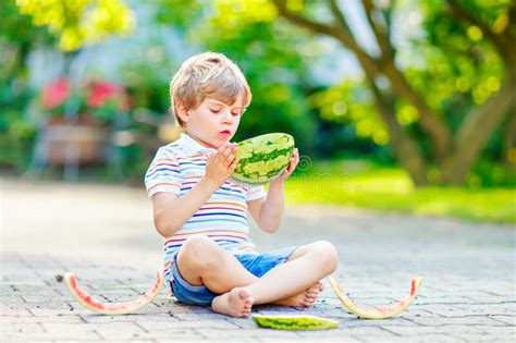 Adorable Little Preschool Kid Boy With Blond Hairs Eating Watermelon In