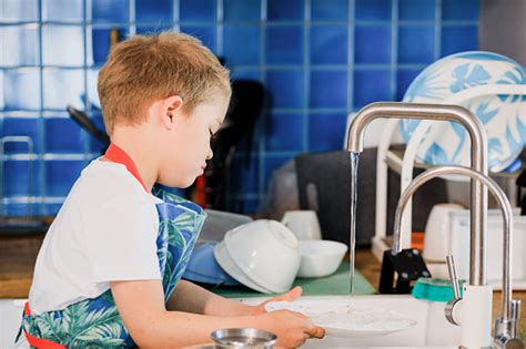 Seorang Anak Lakilaki Di Celemek Mencuci Piring Di Dapur Di Rumah Foto Stok Unduh Gambar