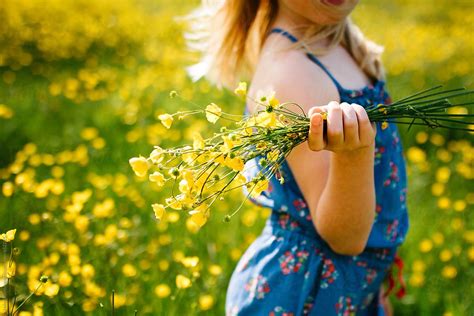 A Little Girl Holding A Bunch Of Wildflowers In A Meadow By Stocksy