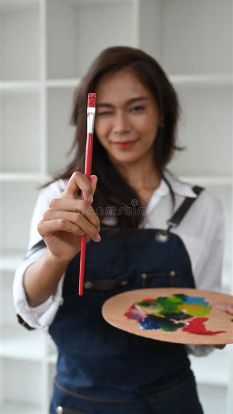 Female Artist With Brush And Paint Palette Standing In Her Art Studio