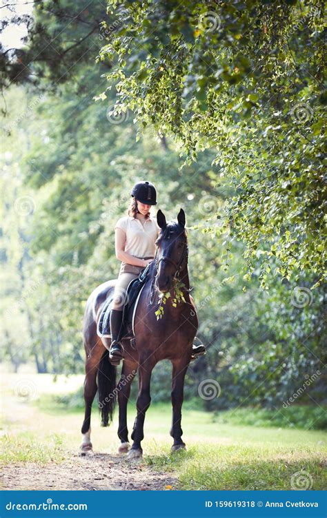 Young Girl Riding Horseback At Early Morning In Sunlight Stock Photo