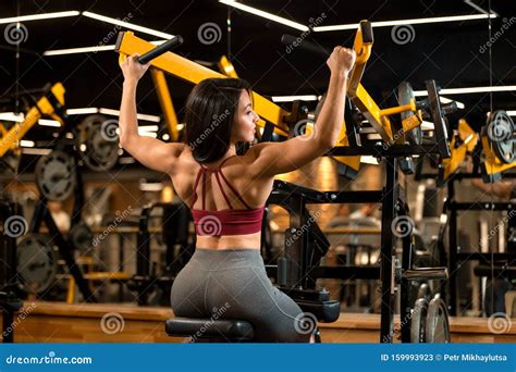 Fitness Brunette Girl Is Sitting And Doing Shoulder Exercises In Trainer Stock Image Image Of