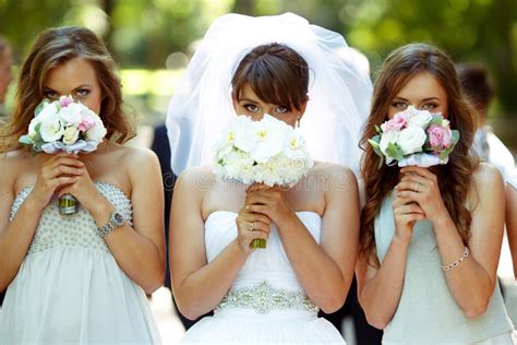 Bride And Bridesmaids Reach Hands With Bouquets To The Cameraman Stock