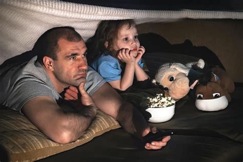 Padre Con Una Hija Pequeña Viendo Una Película En El Sofá Por La Noche