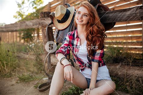 Cheerful Pretty Redhead Young Woman Cowgirl Sitting And Smiling