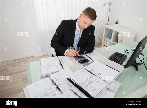 Young Businessman Calculating Tax At Office Desk Stock Photo Alamy