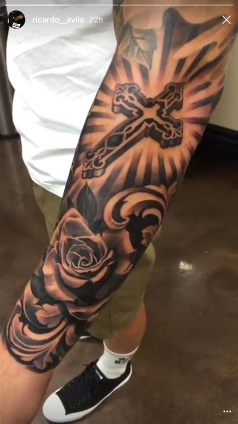 A Man With A Cross And Roses Tattoo On His Arm