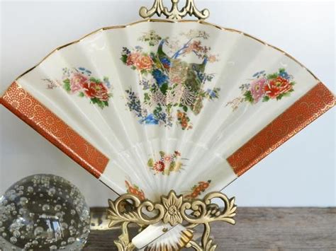 An Ornately Decorated White And Gold Fan Next To A Glass Ball On A