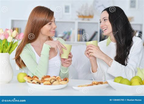 Two Female Friends Sitting At Table And Drinking Tea Stock Image