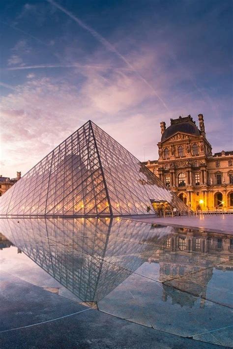 A Large Glass Pyramid In Front Of A Building With A Reflection On The