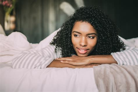 Premium Photo Close Up Of A Pretty Black Woman With Curly Hair Smiling And Lying On Bed