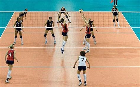 A Group Of Women Playing Volleyball On A Court With The Net In Front Of Them