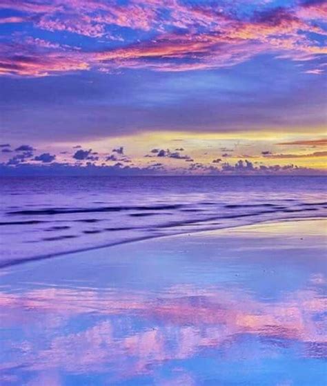 The Sky Is Reflected In The Wet Sand On The Beach As The Sun Goes Down