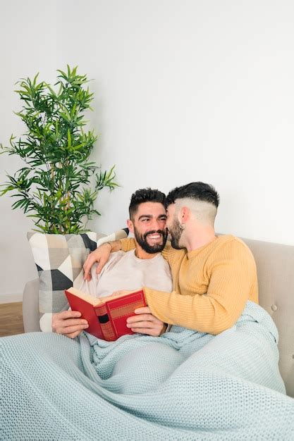 Souriant Aimant Jeune Couple Gay Allongé Sur Un Canapé Dans Une Couverture Bleue Photo Gratuite