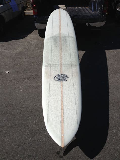 A White Surfboard Sitting On Top Of A Parking Lot Next To A Truck And
