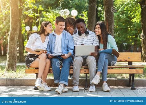 Multiethnic College Friends Resting In Campus Outdoors Using Laptop