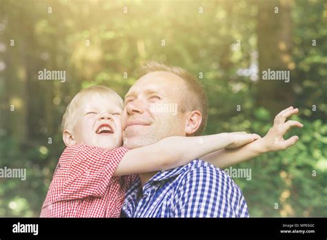 father and son hugging smiling and bask in the sun masculinity concept emotional portrait of