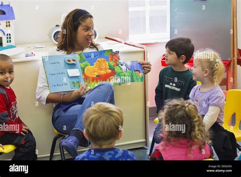 Hispanic Teacher Reading Book To Young Students In Preschool Stock