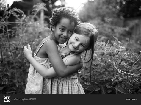 Two Little Girls Hugging In A Garden In Black And White Stock Photo