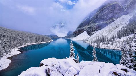 River Between Snow Covered Mountains And Pine Trees During Daytime 4k