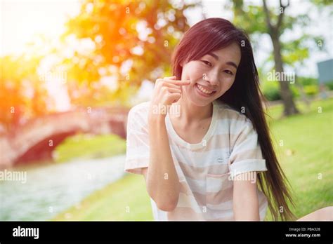 Cute Asian Woman Smile With Finger Dimples Cheek In The Park Stock