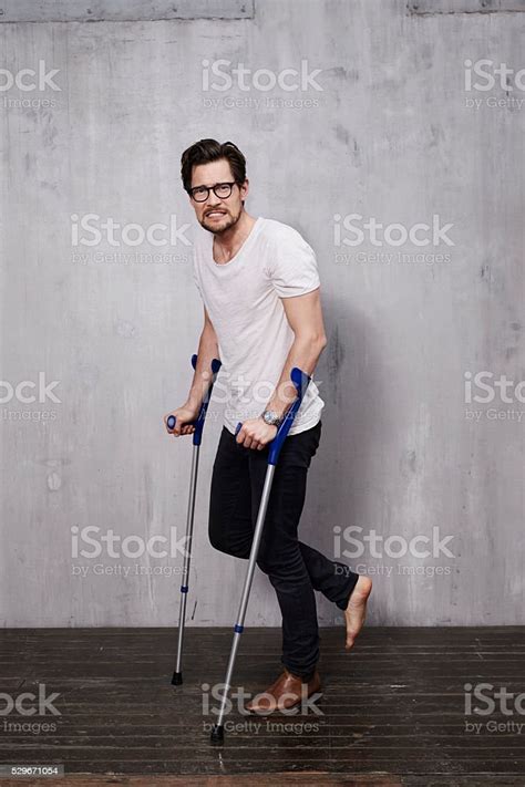 Anxious Young Man On Crutches In Studio Stock Photo Download Image