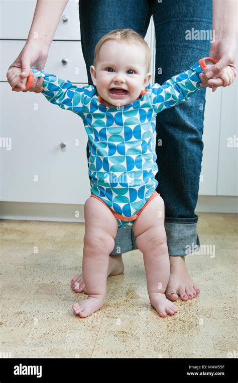 A Mother Helping Her Six Month Old Baby Stand Up Stock Photo Alamy