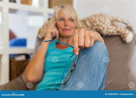 Mature Woman Lies On A Seating Furniture While She Takes A Phone Call