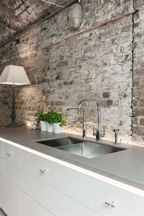 A Kitchen With An Old Brick Wall And Stainless Steel Sink In The Center