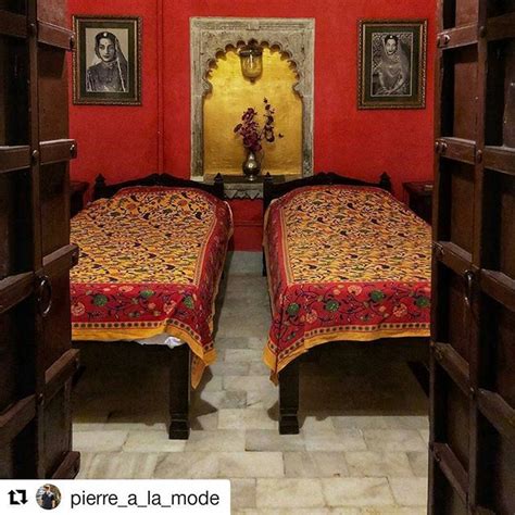 Two Beds In A Room With Red Walls And Pictures On The Wall Behind Them