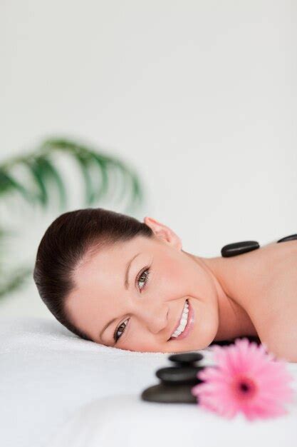 Retrato De Uma Jovem Mulher Com Pedras De Massagem E Uma Gerbera Rosa Foto Premium