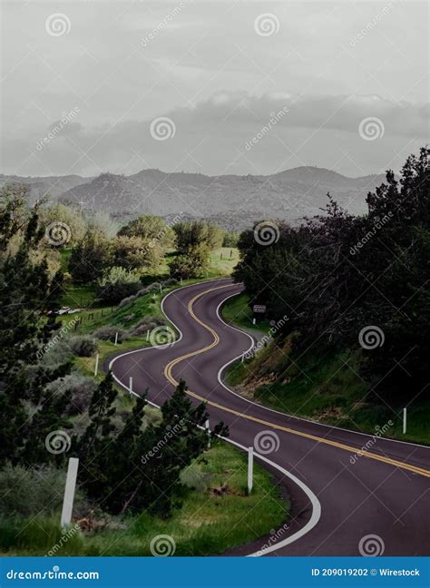 Vertical Shot Of A Curvy Road With Forested Mountains In The Background